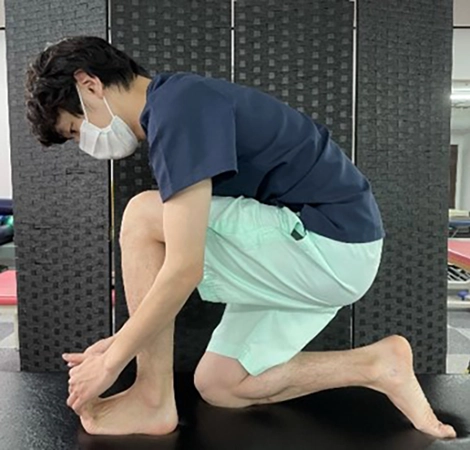 外脛骨障害のリハビリ_足趾を上に持ち上げた状態で前に体重をかけてストレッチ