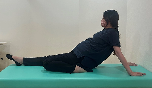 片方の膝を曲げてお尻の横に足を置き、体を後ろに倒す